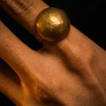 Copper ring on a person's finger against a dark background
